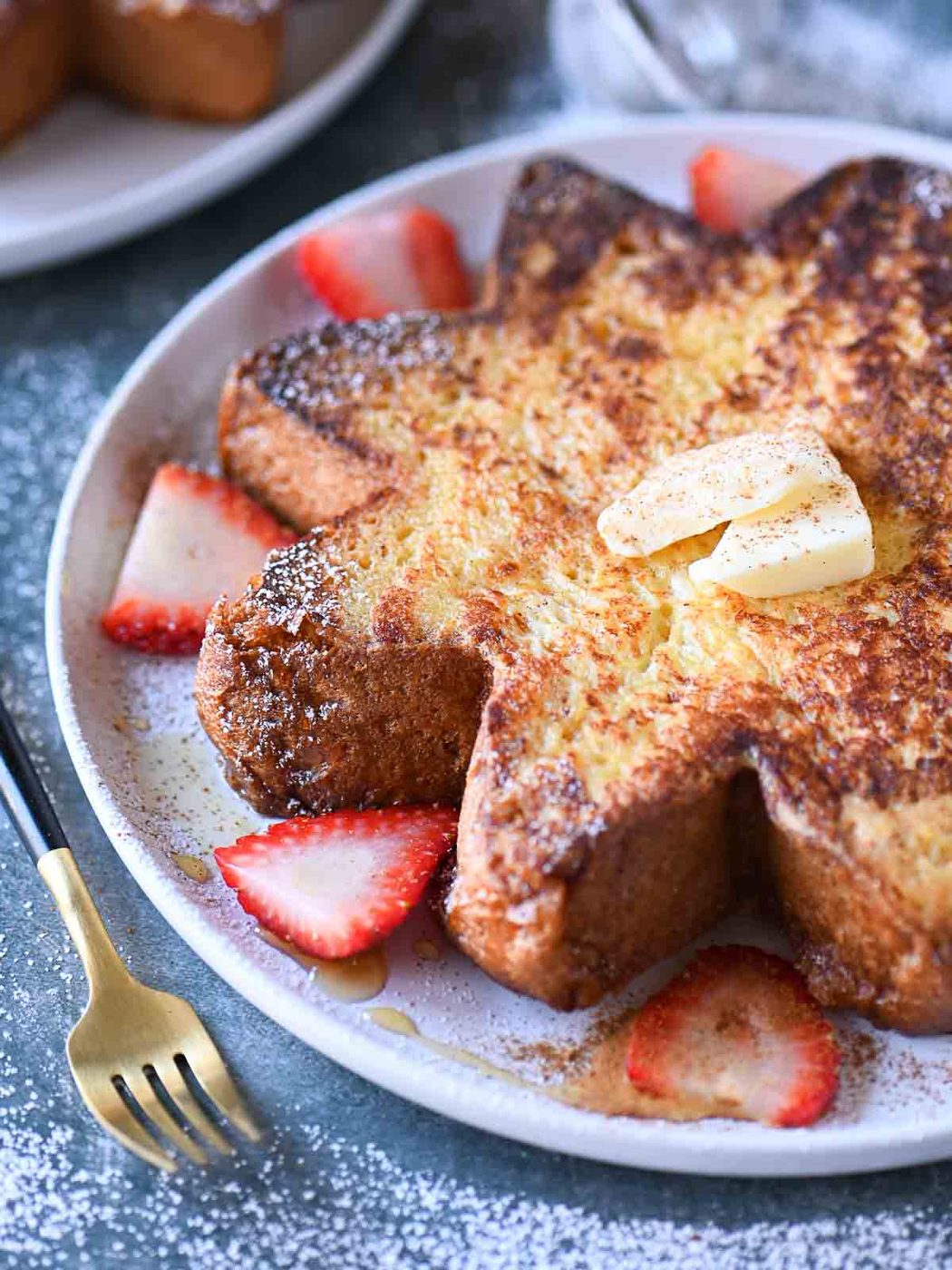 Angled view of star French toast with strawberries on a white plate.