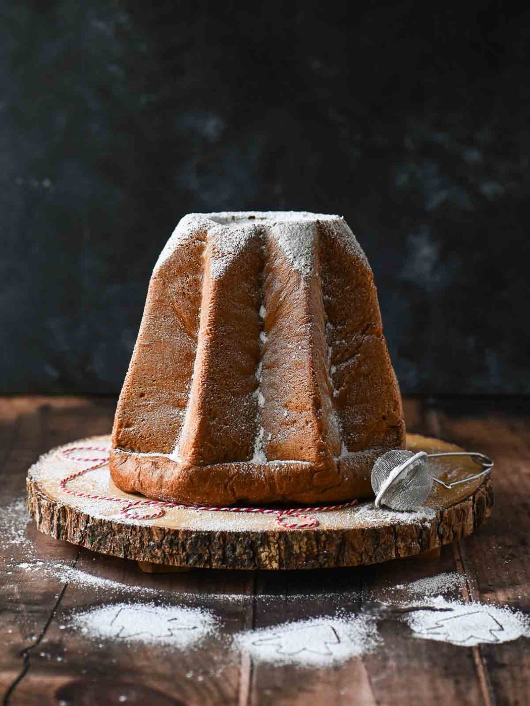 Italian pandoro on a wood board with powdered sugar on top.