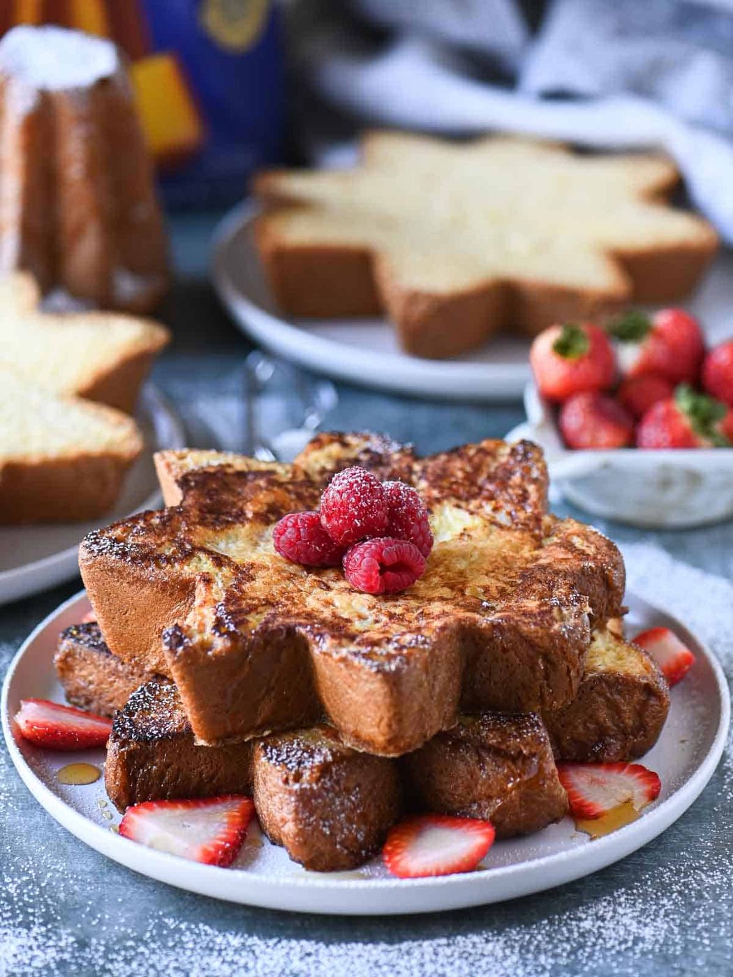 Pandoro French toast stacked on a plate with lots of red berries.