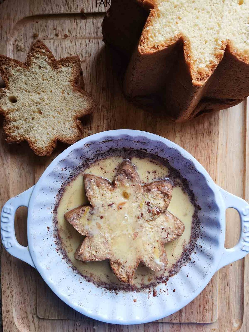 A slice of pandoro in french toast custard in a white dish.