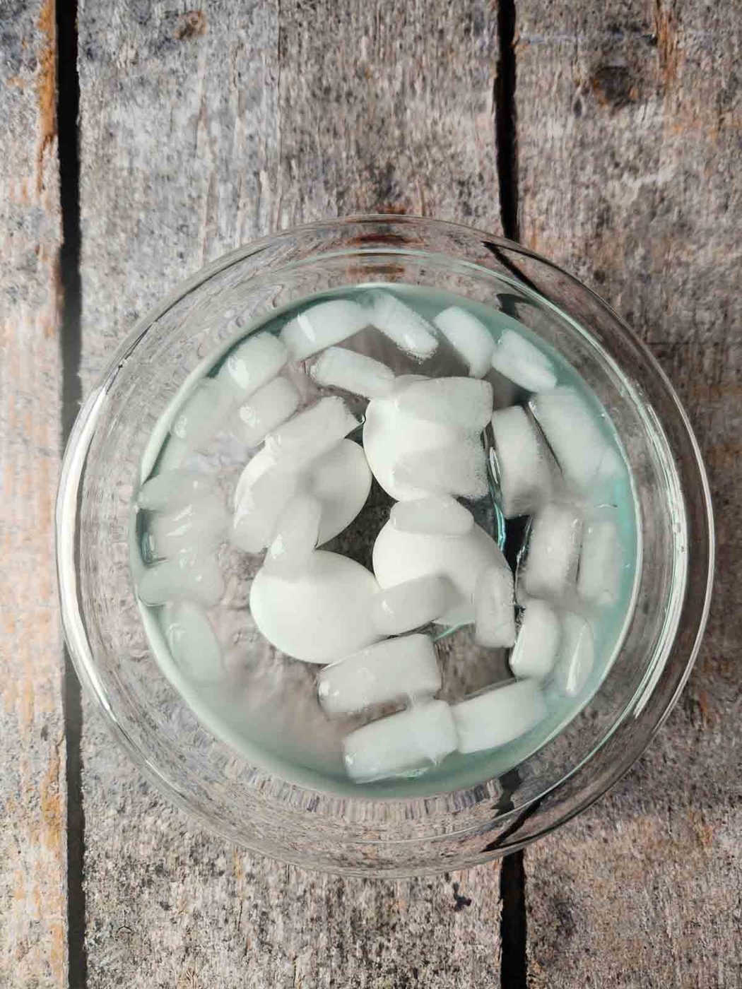 Eggs in a clear bowl of water with ice.