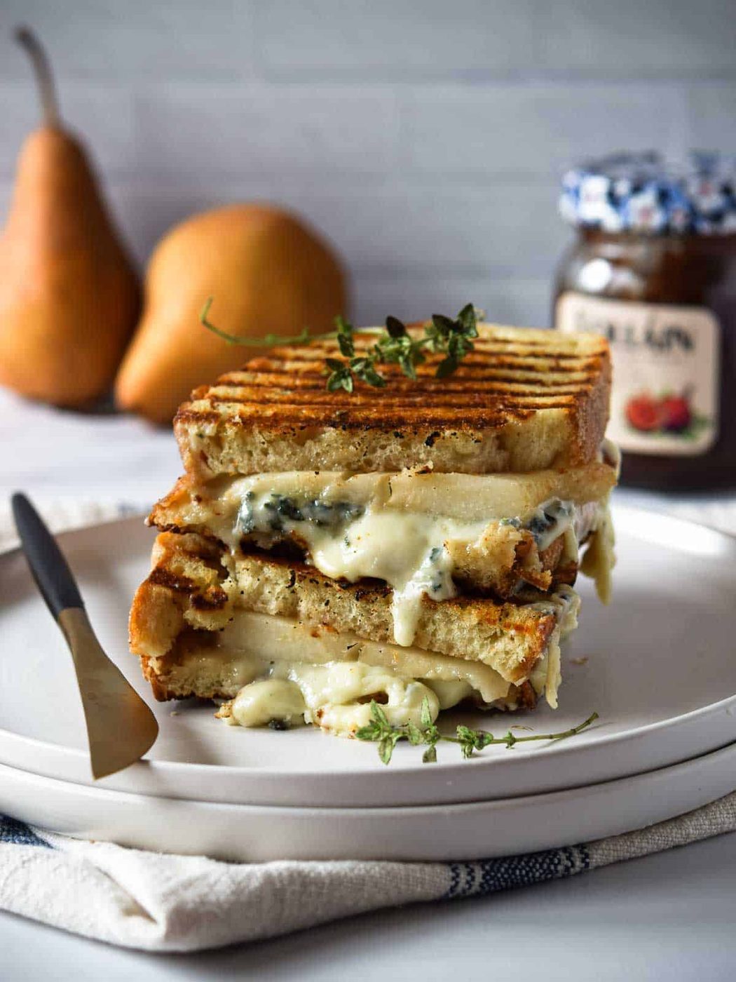 Gorgonzola and pear grilled cheese stacked and melty on a white plate.