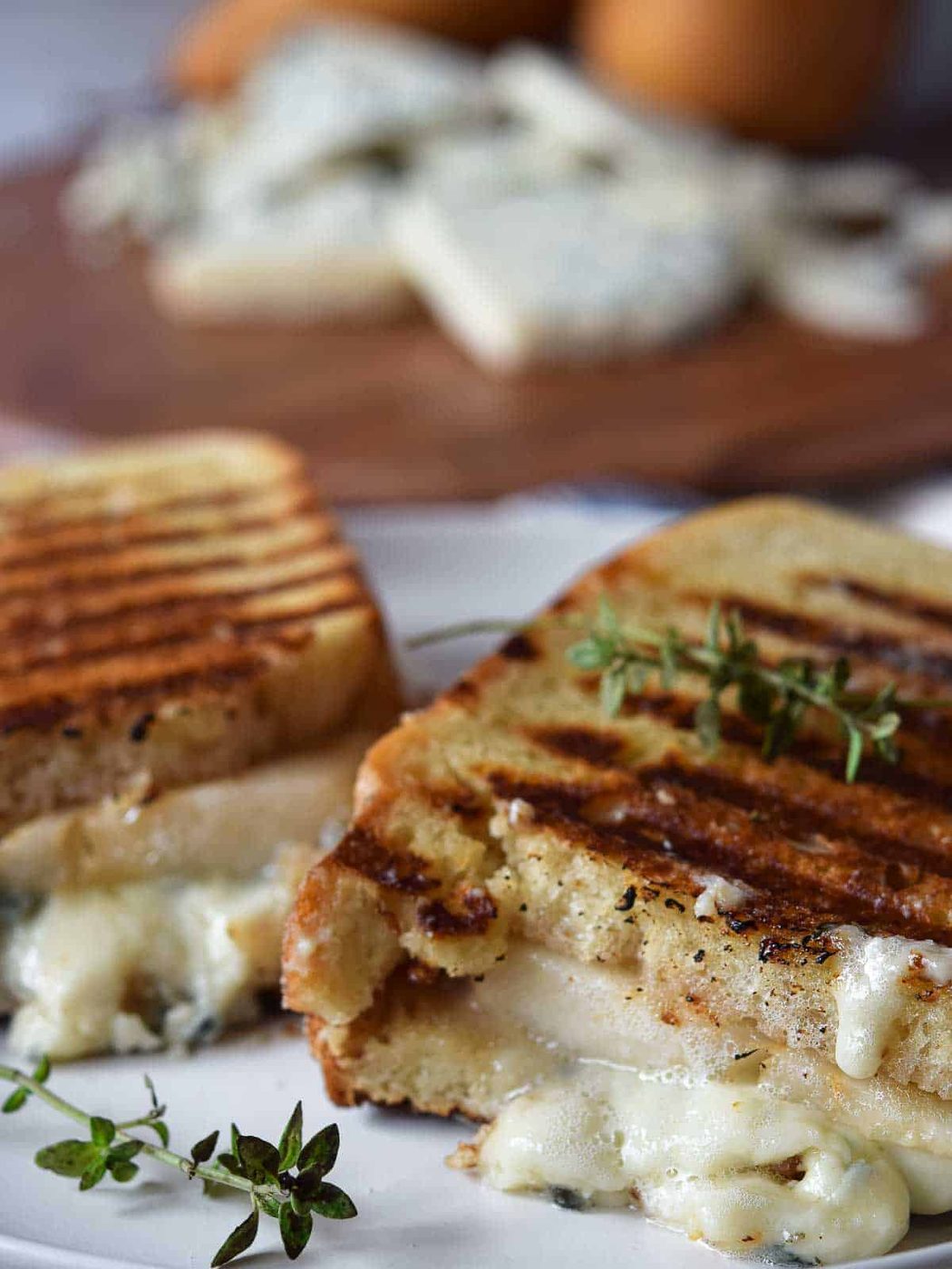 Gorgonzola grilled cheese cut in half on a white plate.