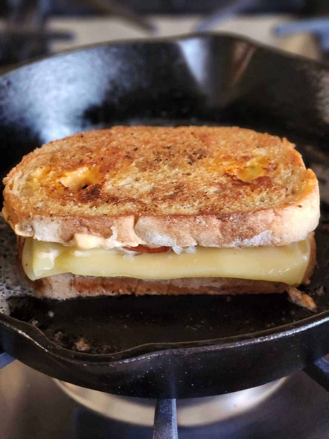 Reuben sandwich grilling in a cast iron skillet.