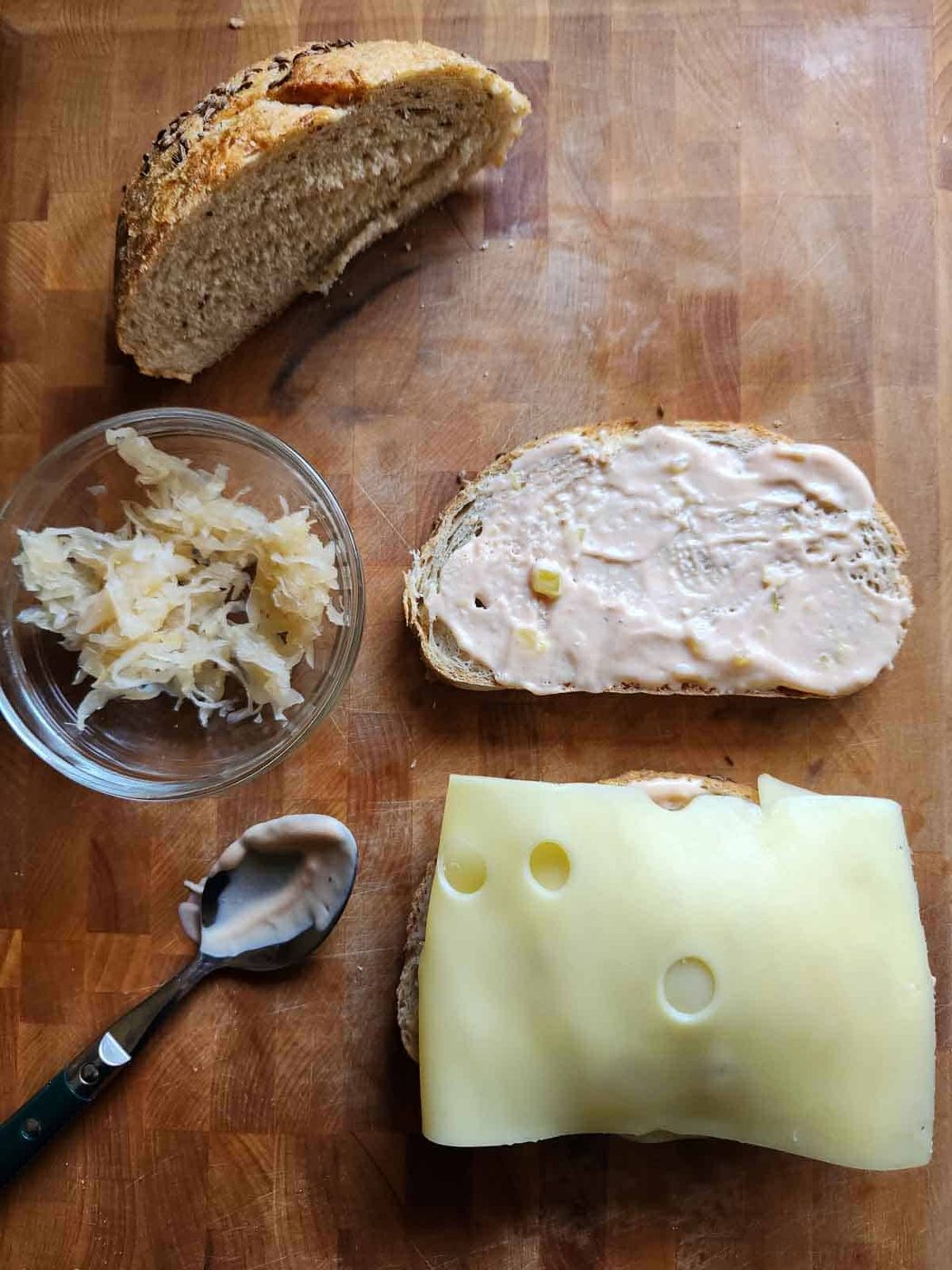 Bread, sauerkraut and cheese on a cutting board.