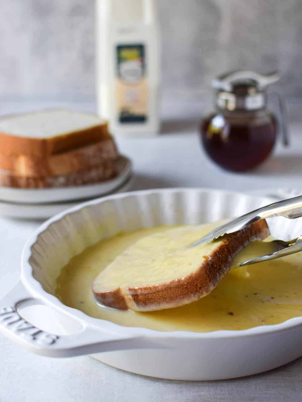 Bread being dipped into an egg custard for French toast.
