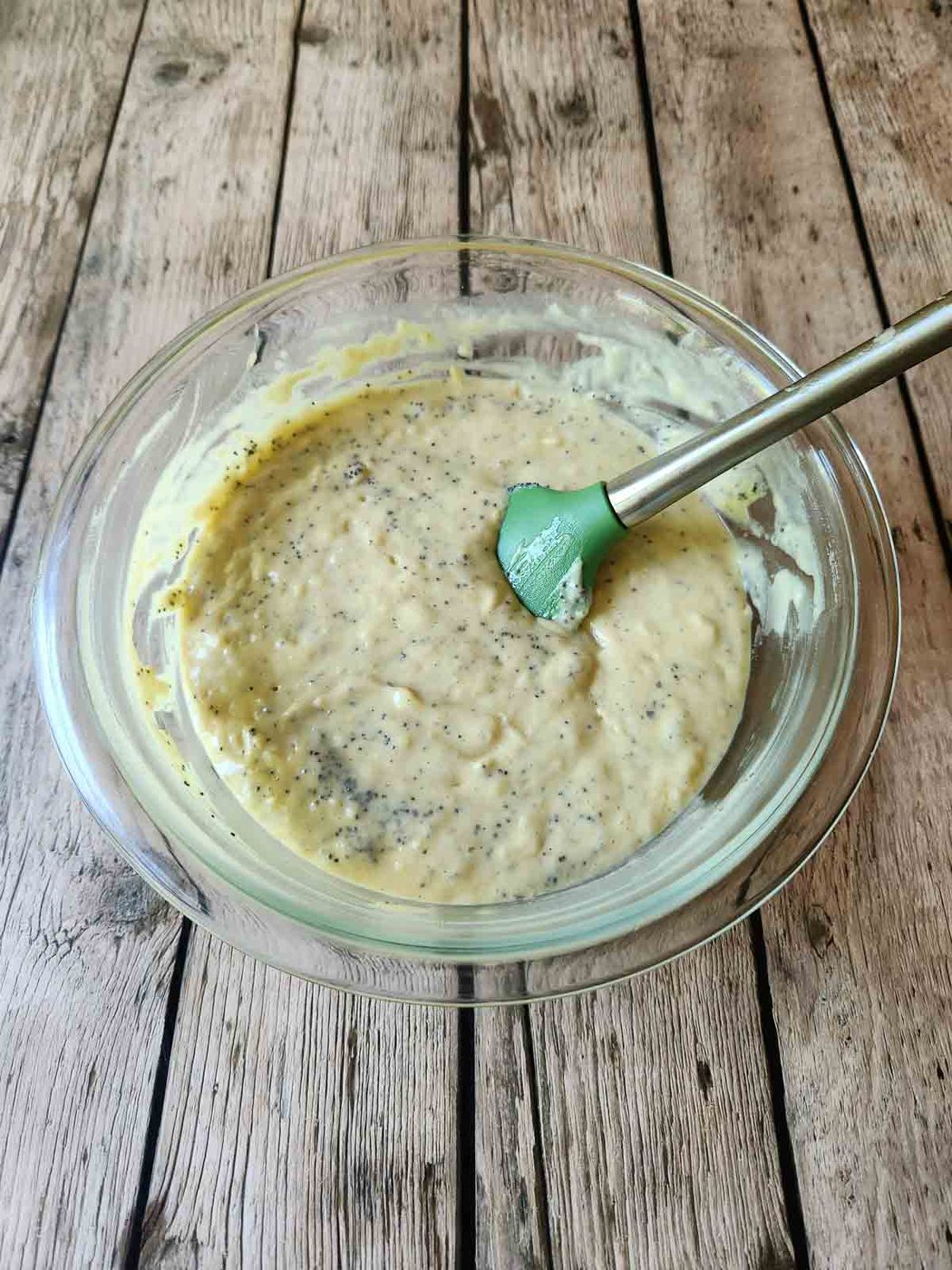 Muffin batter in clear bowl with a spatula.