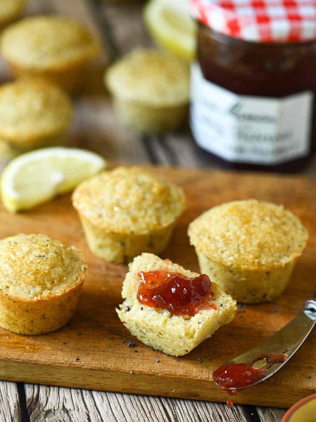Mini muffins cut open with strawberry jam on them.