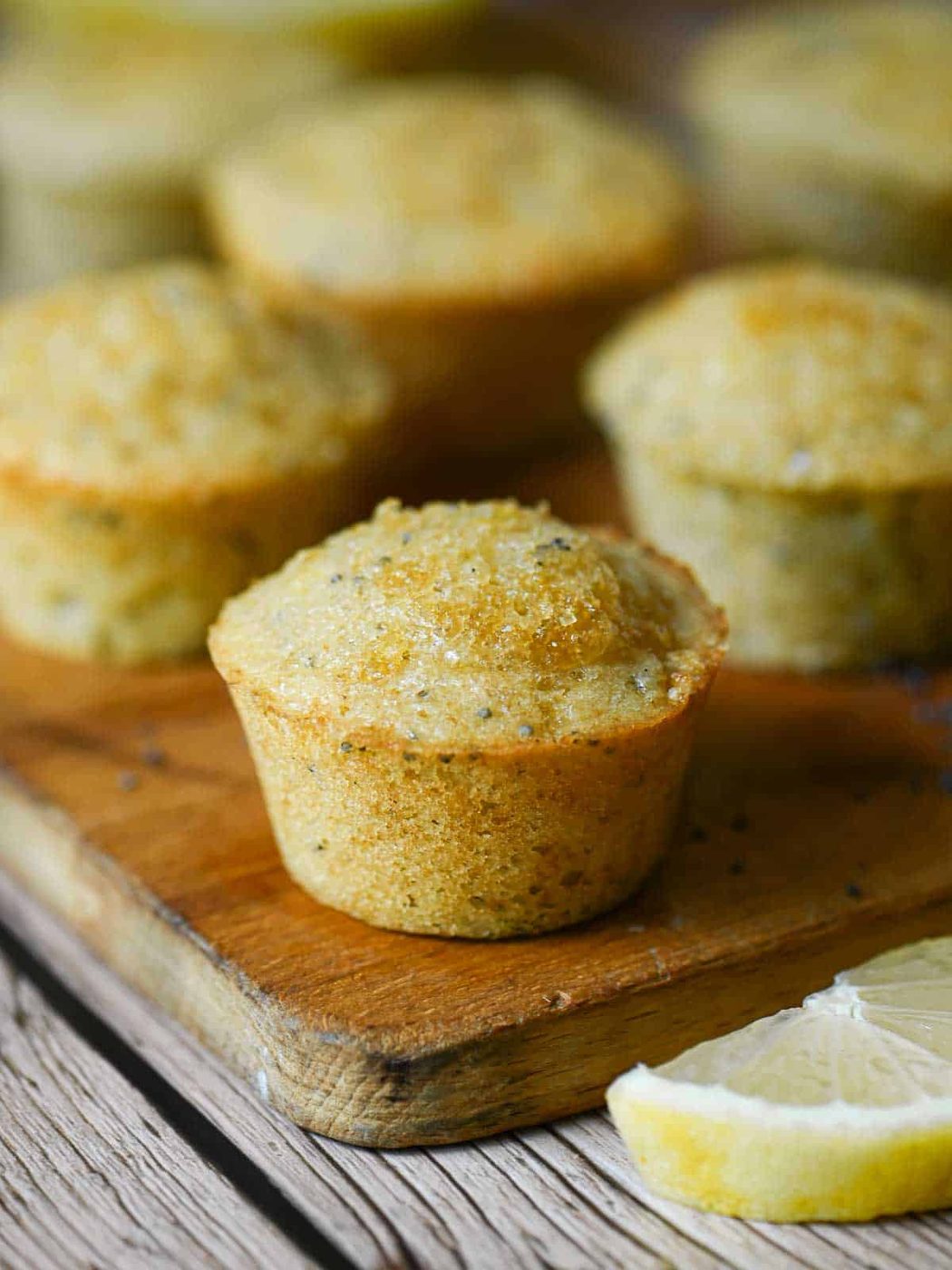 Close-up of a mini lemon muffin on a wood board.