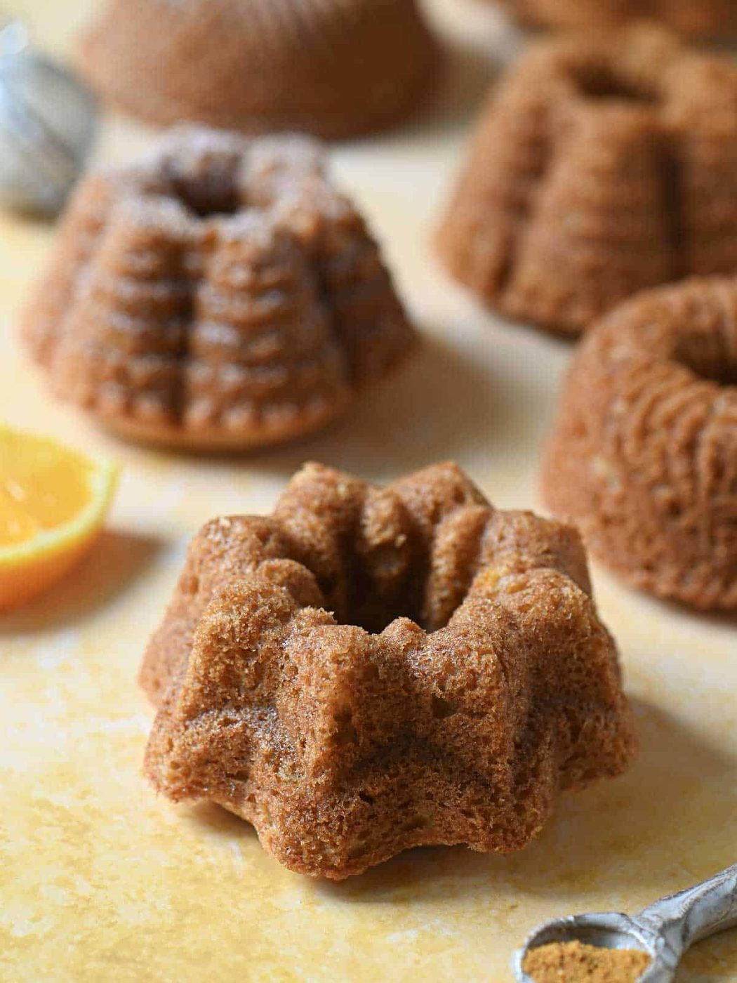 Close-up of mini bundt cakes on an orange surface.