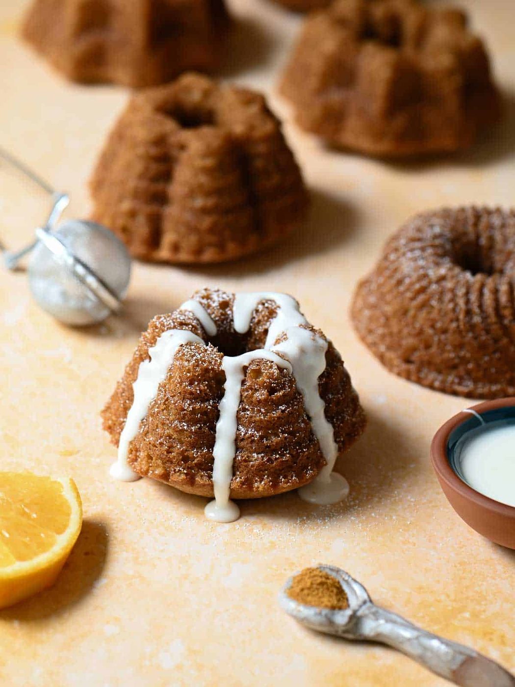 Mini bundt cake with icing on an orange surface.