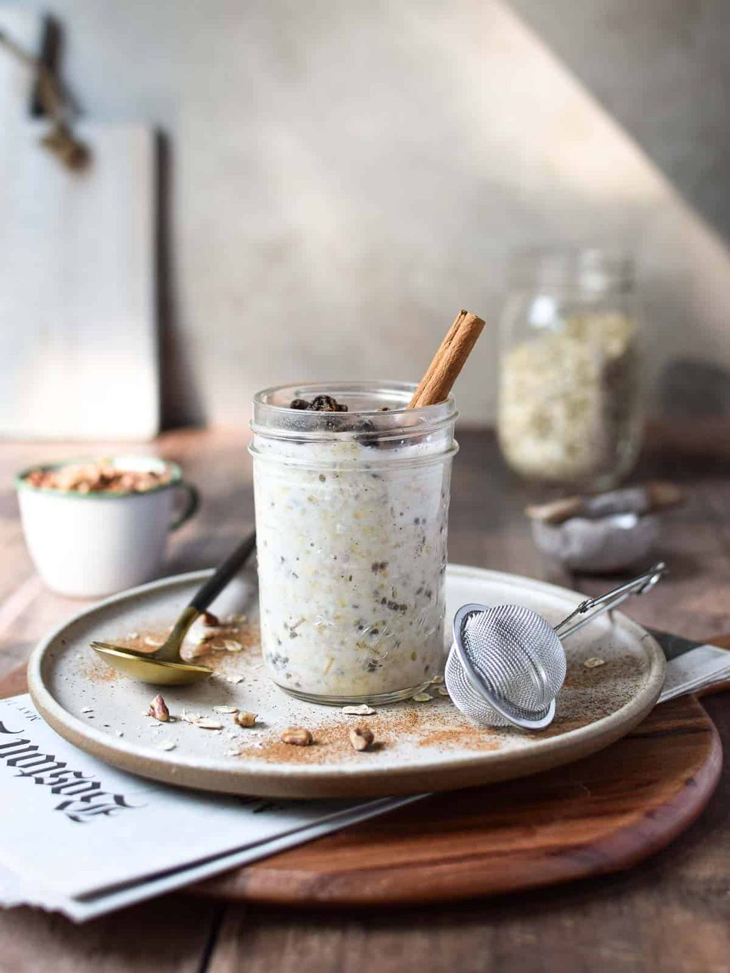 Eye-level view of overnight oats in a jar on a wood surface with the Sunday paper showing.