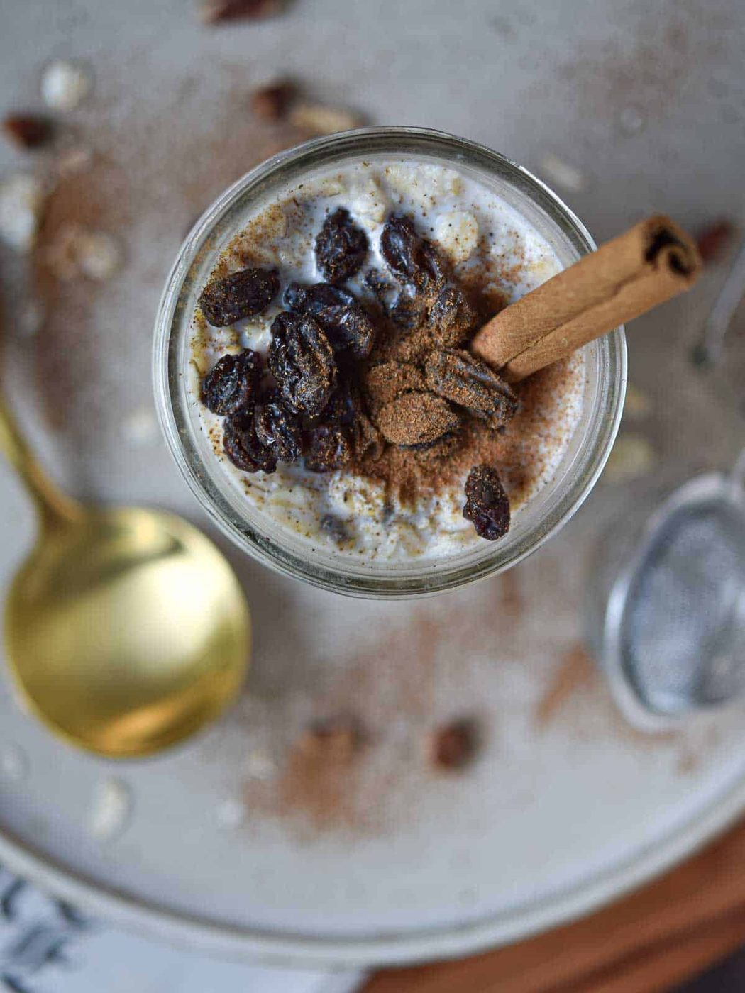 Overhead view of overnight oats in a jar with raisins and a cinnamon stick.