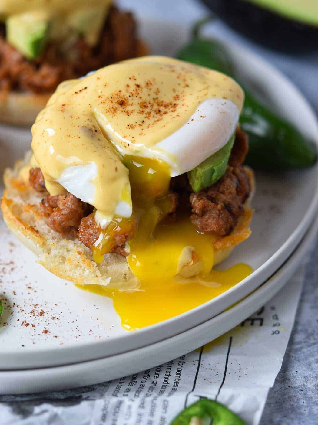 Close-up of eggs benedict with a runny yolk on a white plate.