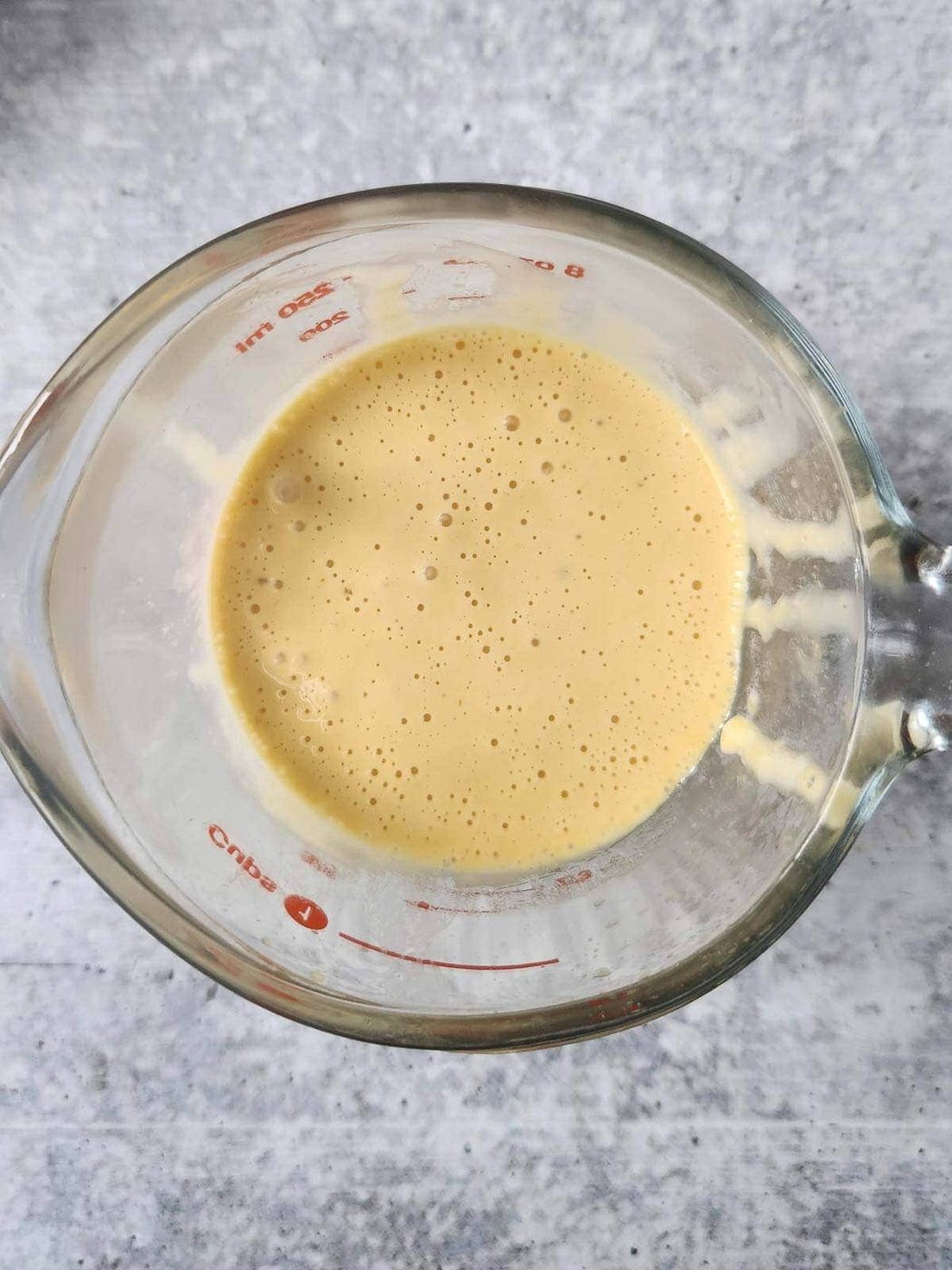 Clear container of hollandaise sauce.