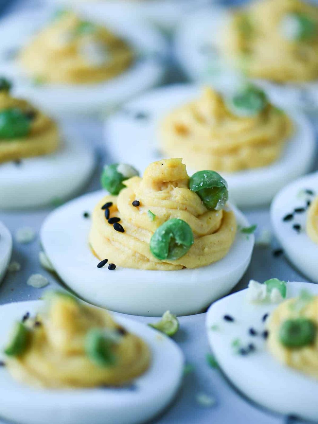 Close-up of miso deviled eggs with wasabi peas on top.