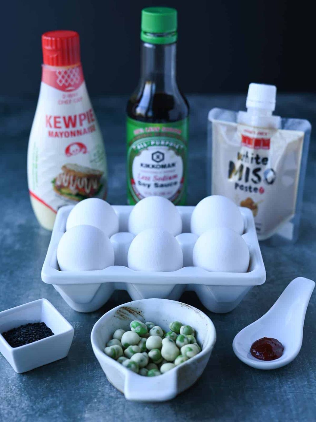 Ingredients for miso deviled eggs on a blue surface.