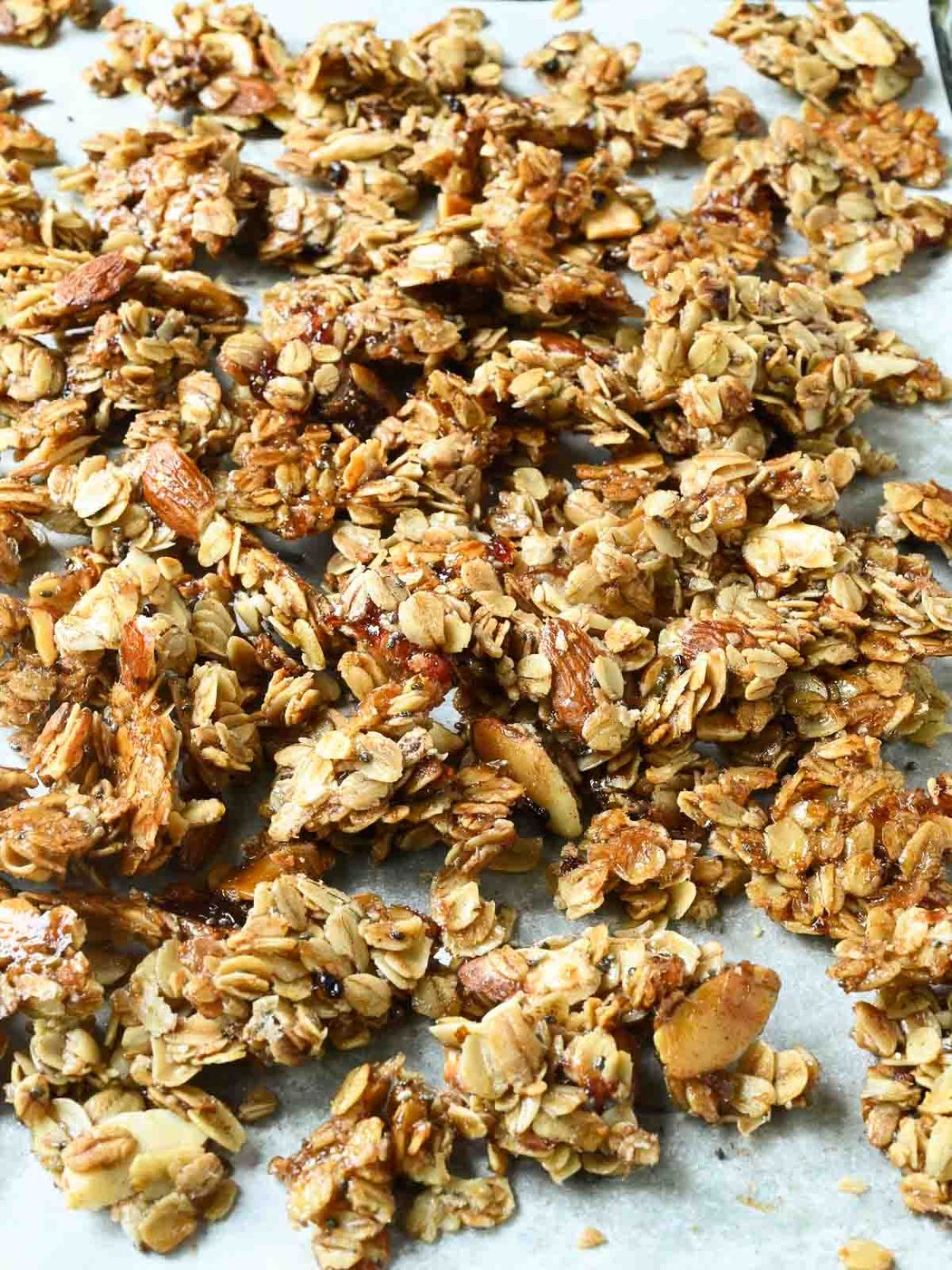 Cooked granola on a baking sheet broken up into clusters.