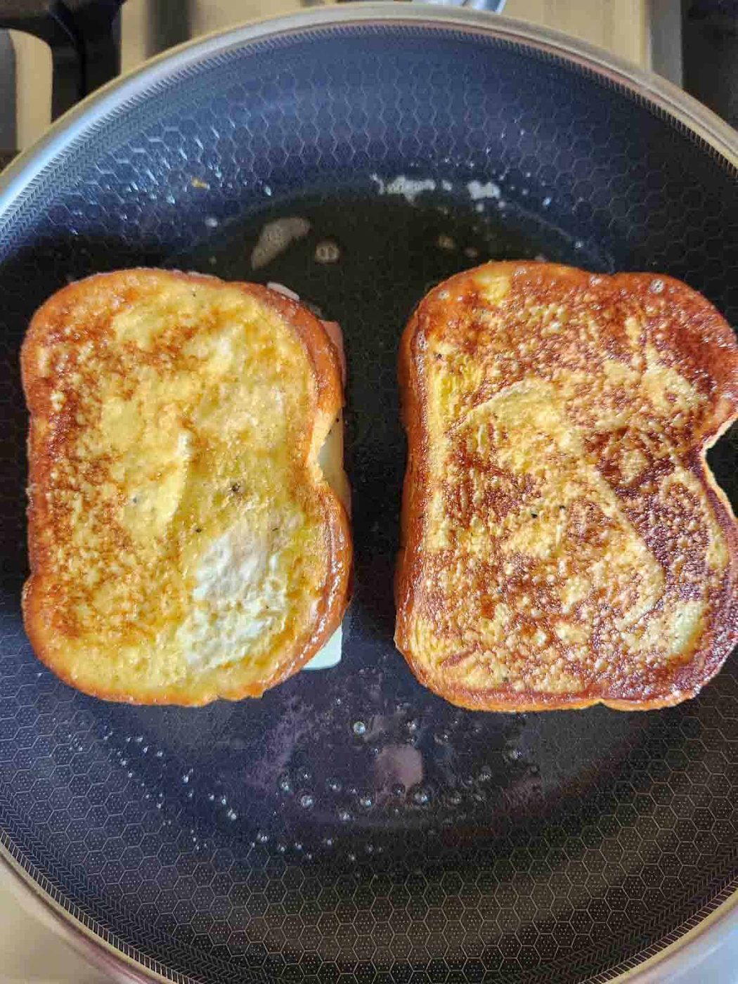 Overhead of cooked, golden brown monte cristo's in a frying pan.