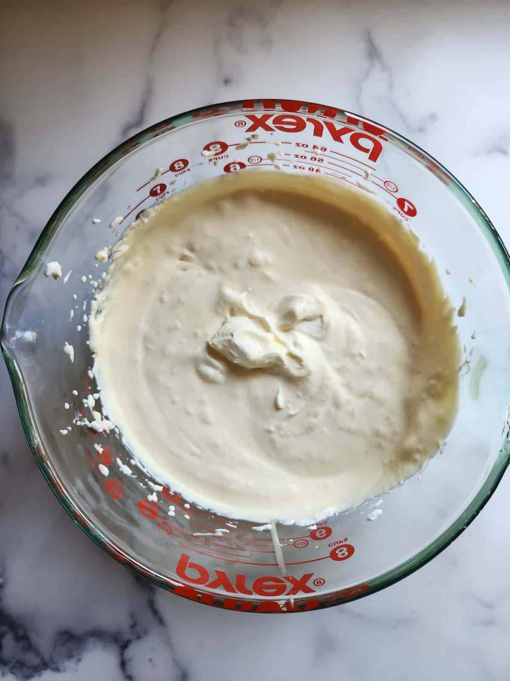 Whipped cream and condensed milk in a clear bowl.