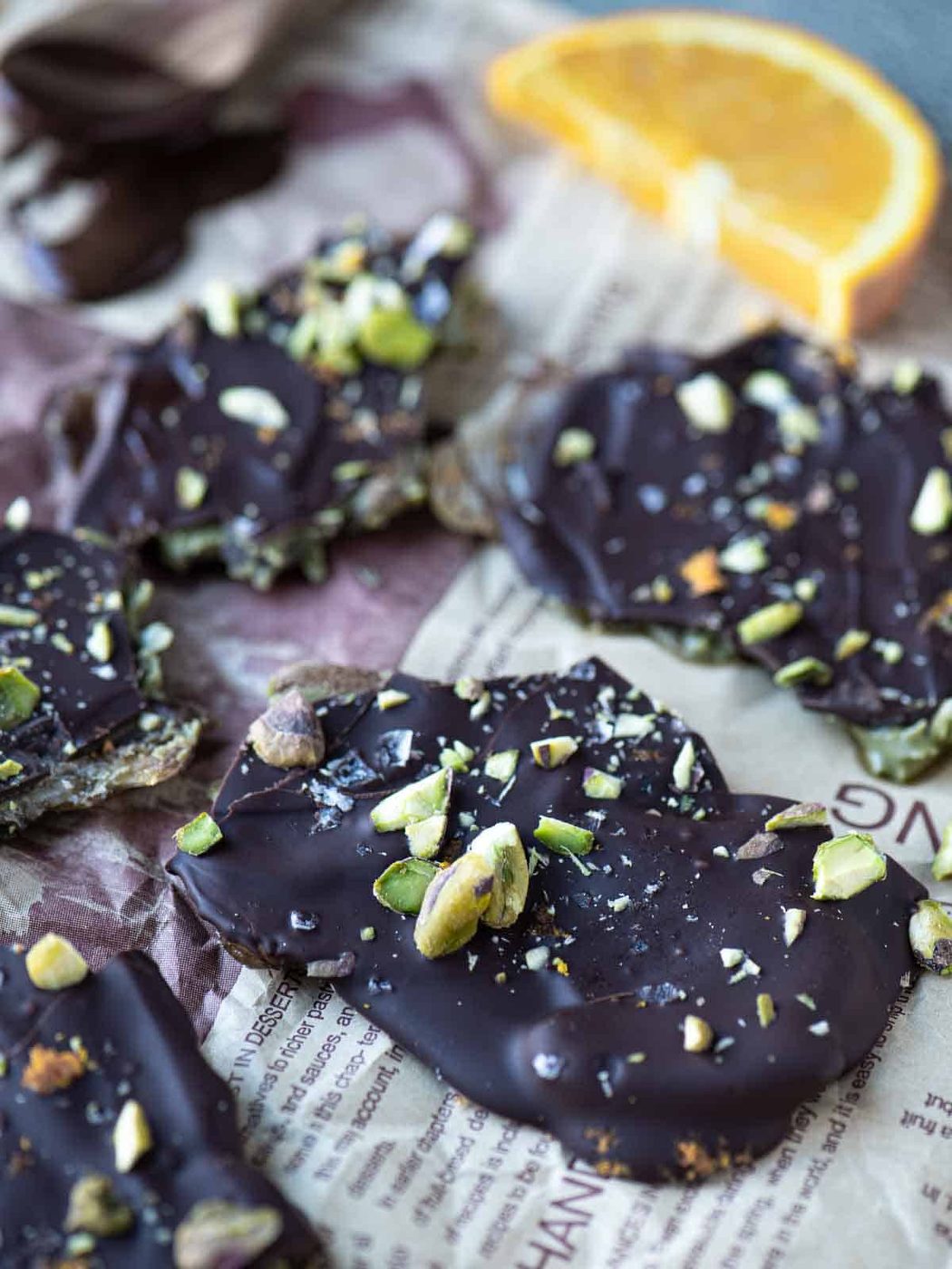 Pieces of date bark on brown parchment with an orange in the bachground.