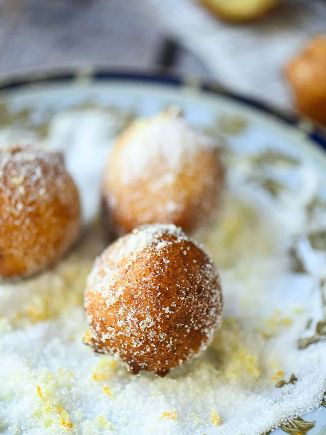 Donut being rolled in a plate of orange sugar.