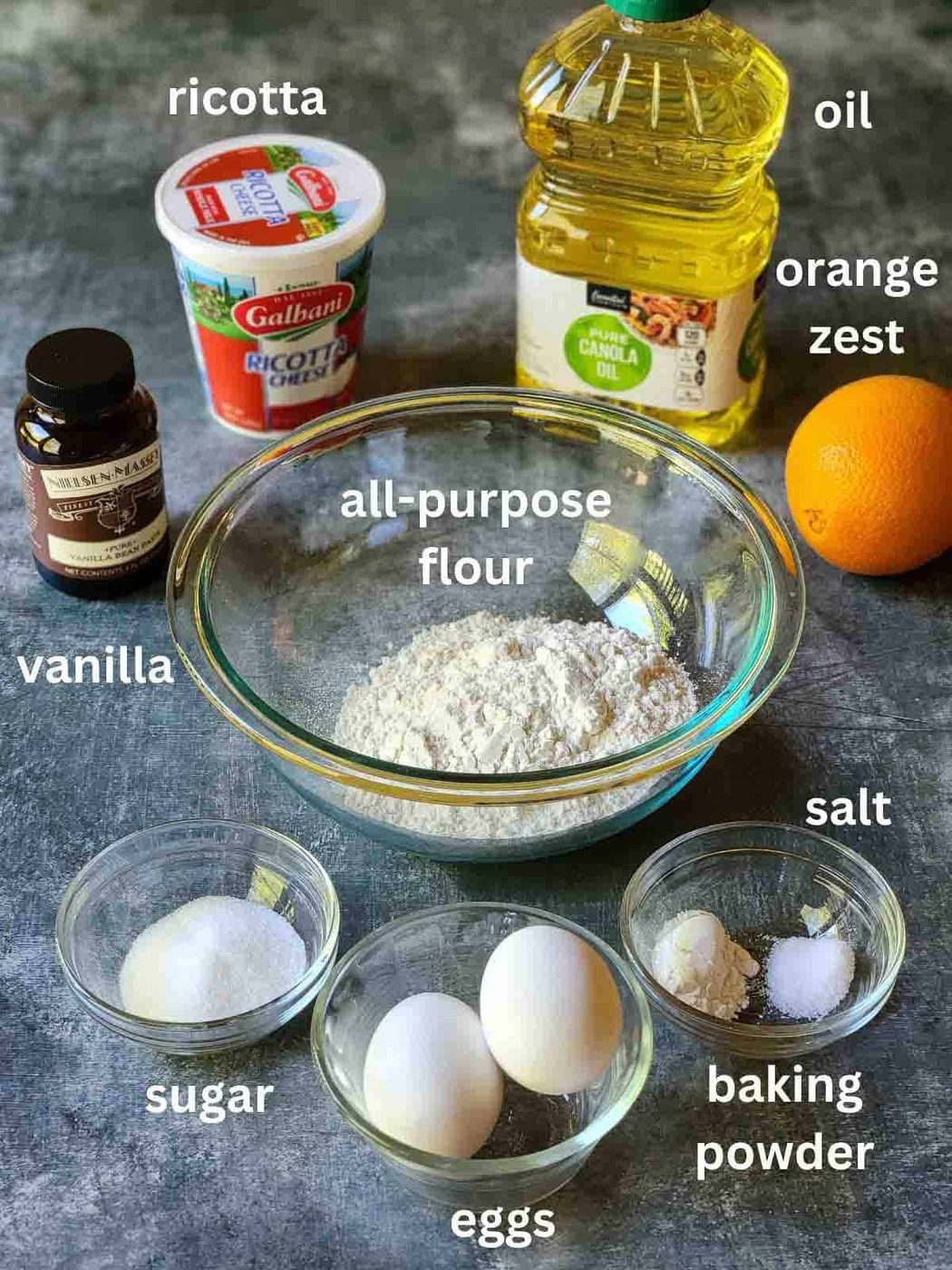 Ingredients for orange ricotta donuts on a blue surface.
