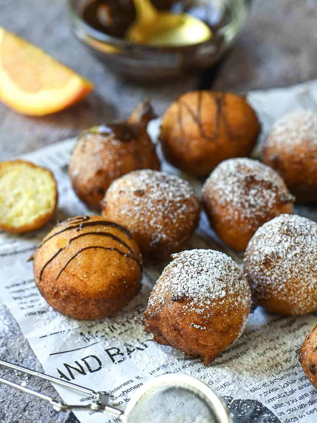 Orange ricotta donuts on parchment paper with powdered sugar.
