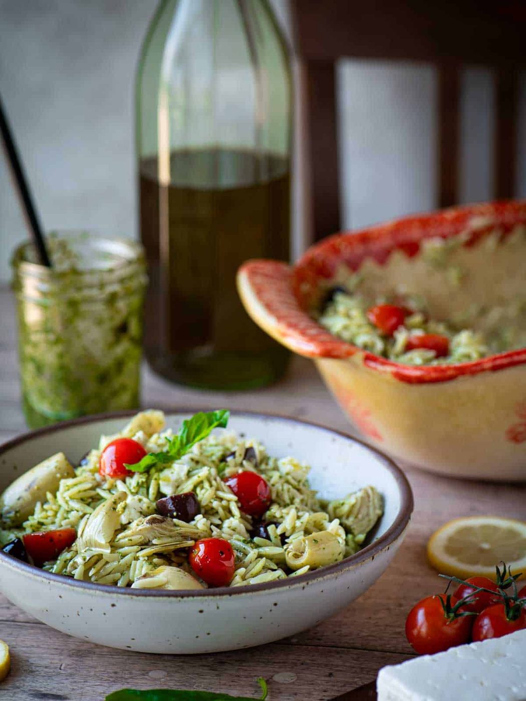 Orzo pesto salad in a beige bowl in a kitchen table.