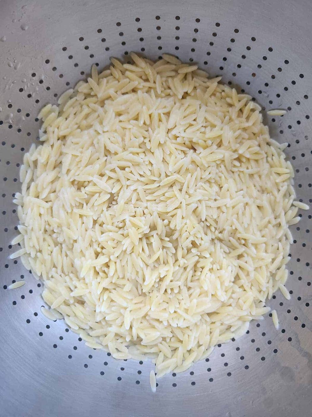 Boiled and drained orzo in a colander.