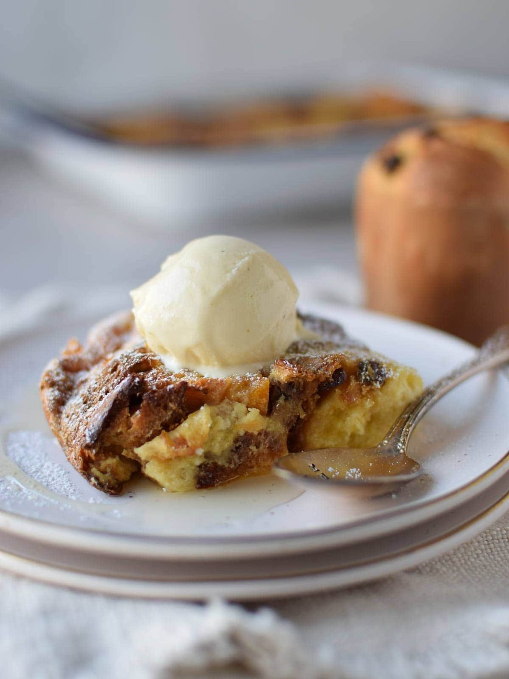 Eye-level view of bread pudding with ice cream on top on a white plate.