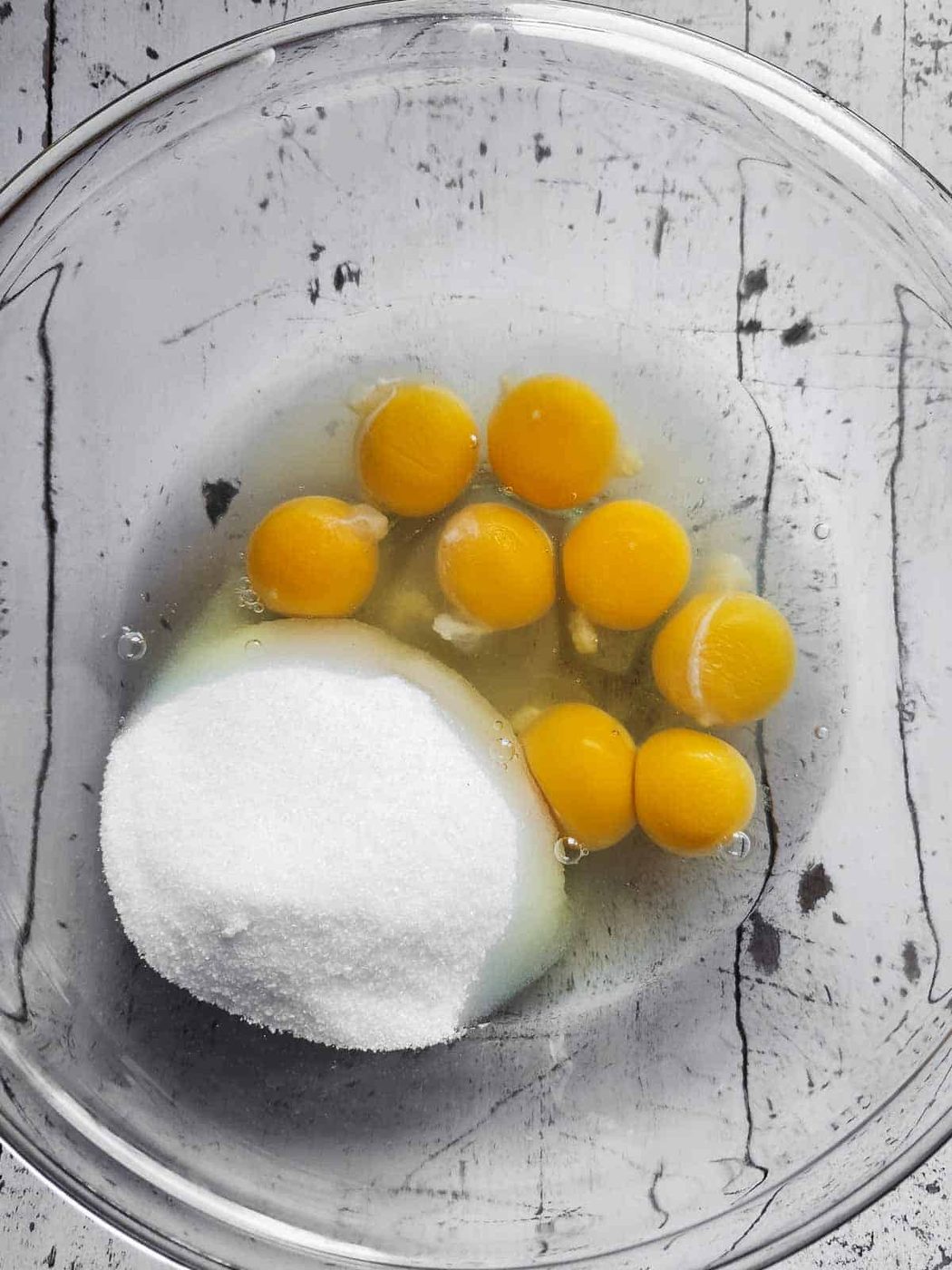 Eggs and sugar in a clear bowl for bread pudding.