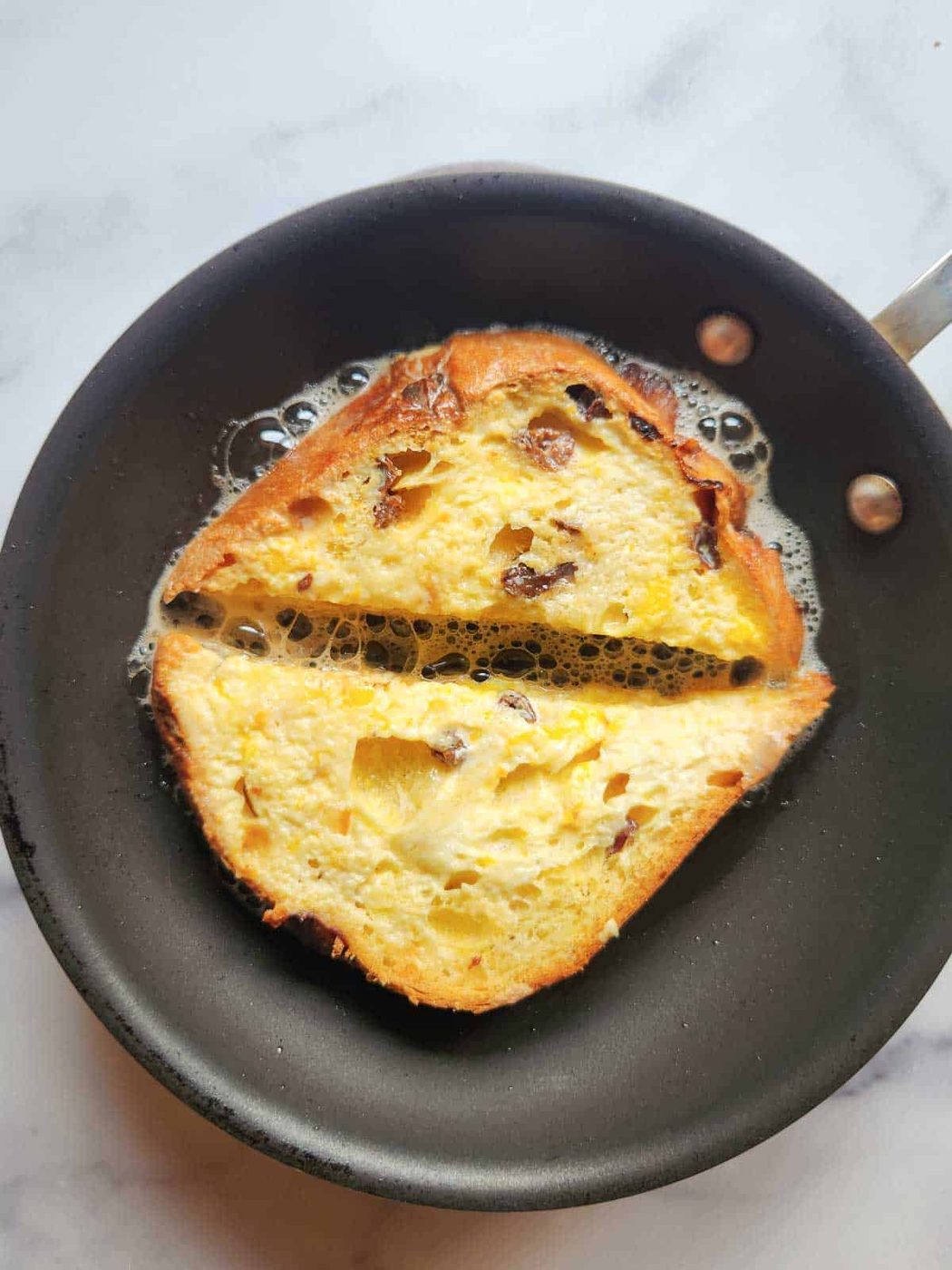 Panettone cooking in skillet for French toast.