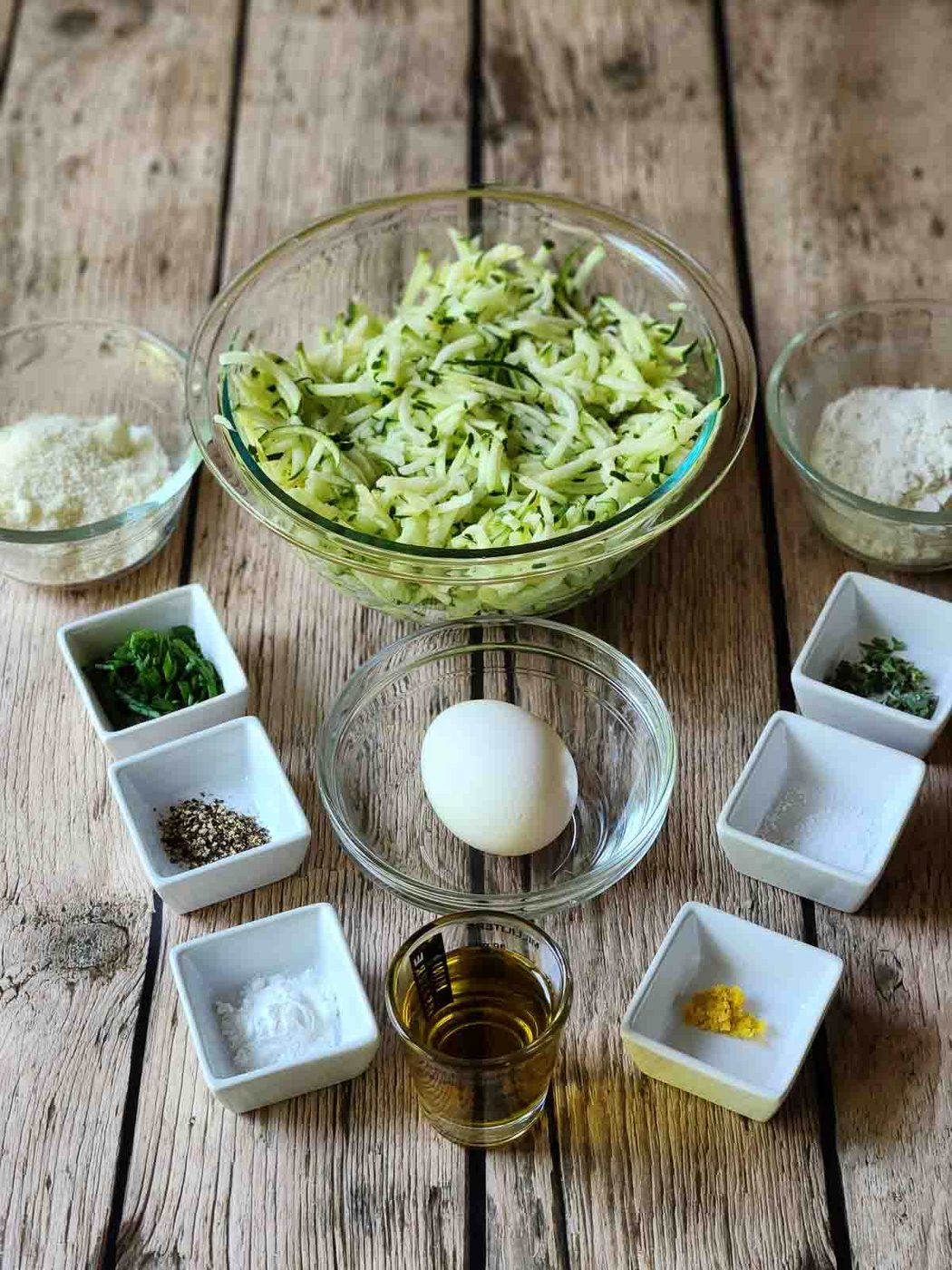 Ingredients for zucchini pancakes on a wood table.