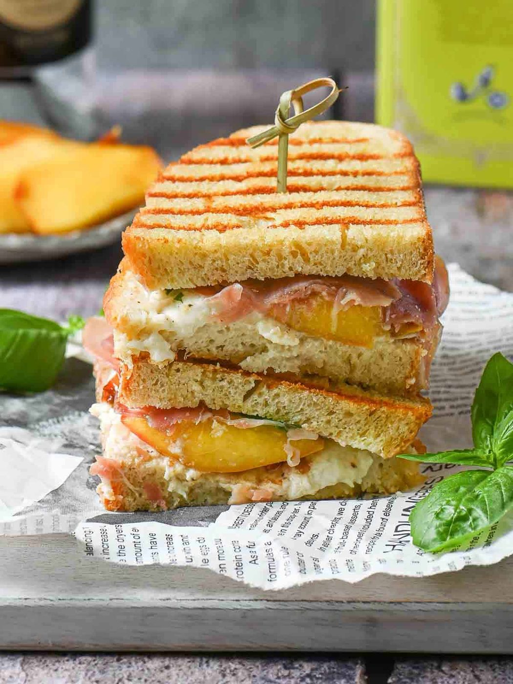 Peach panini sandwiches stacked on top of each other on a grey board.