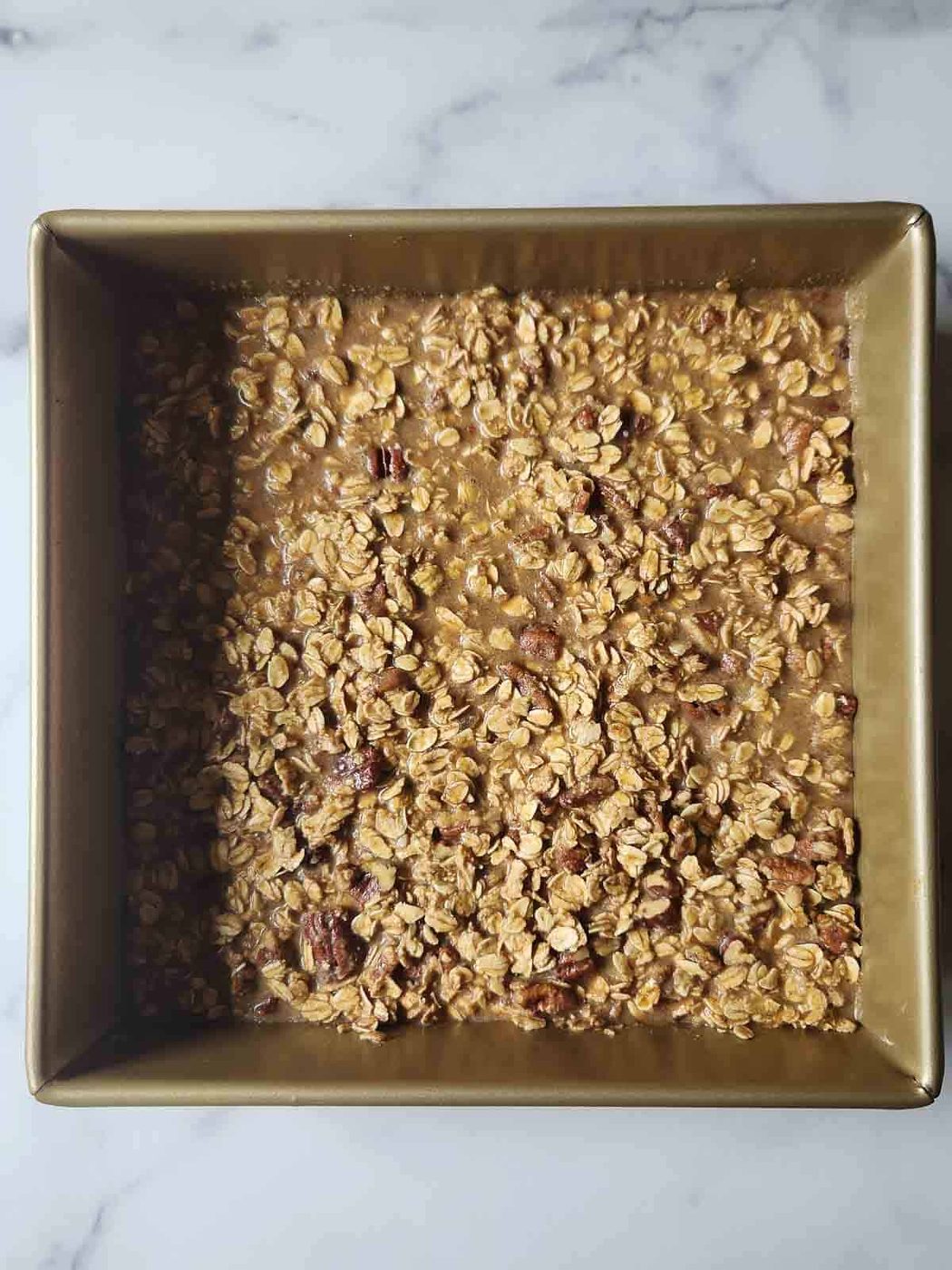 Prepared batter for pecan pie oatmeal in a square pan.