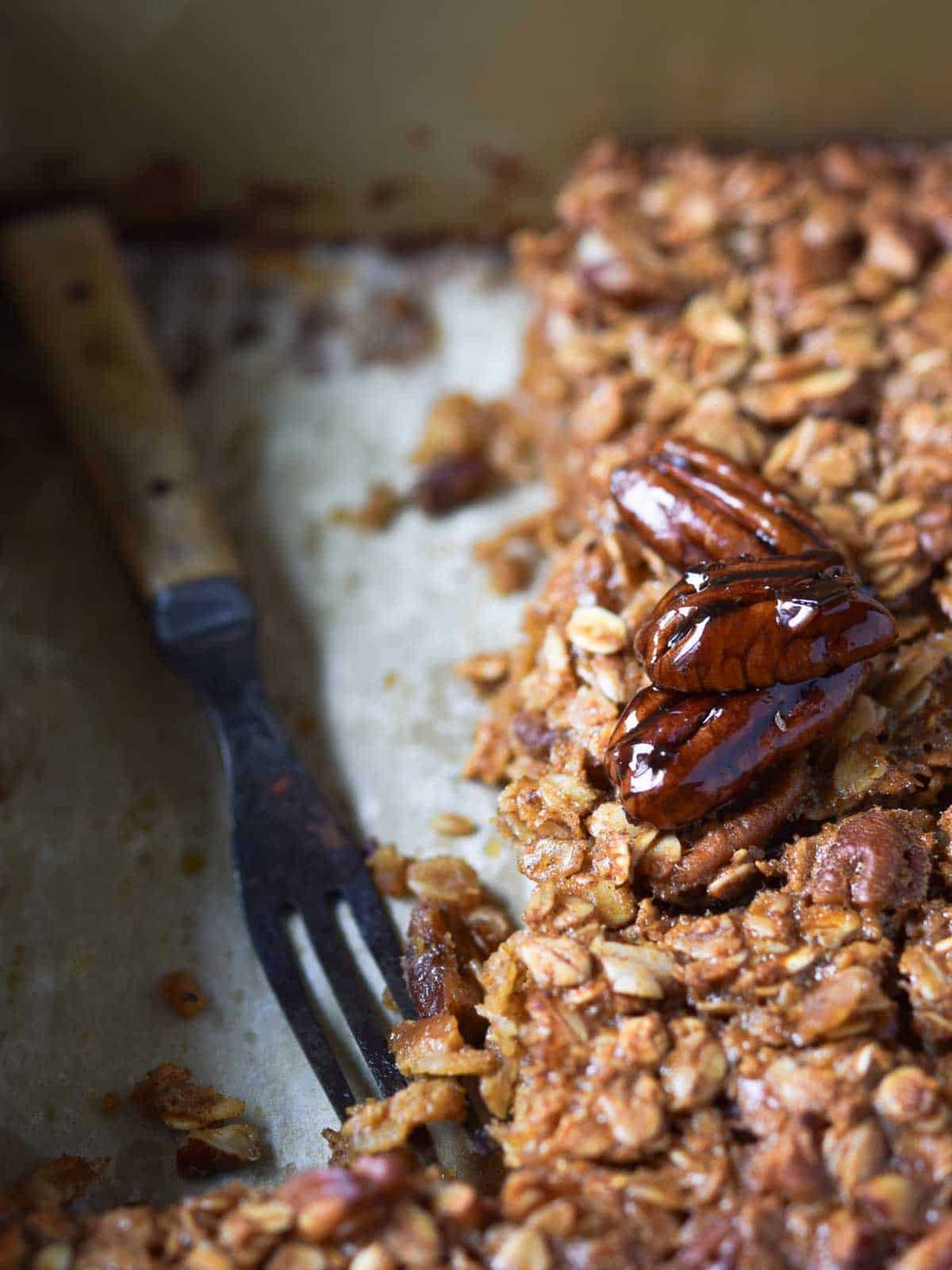 Pecan pie oatmeal in a pan, with a large piece taken out and a fork left in its place.