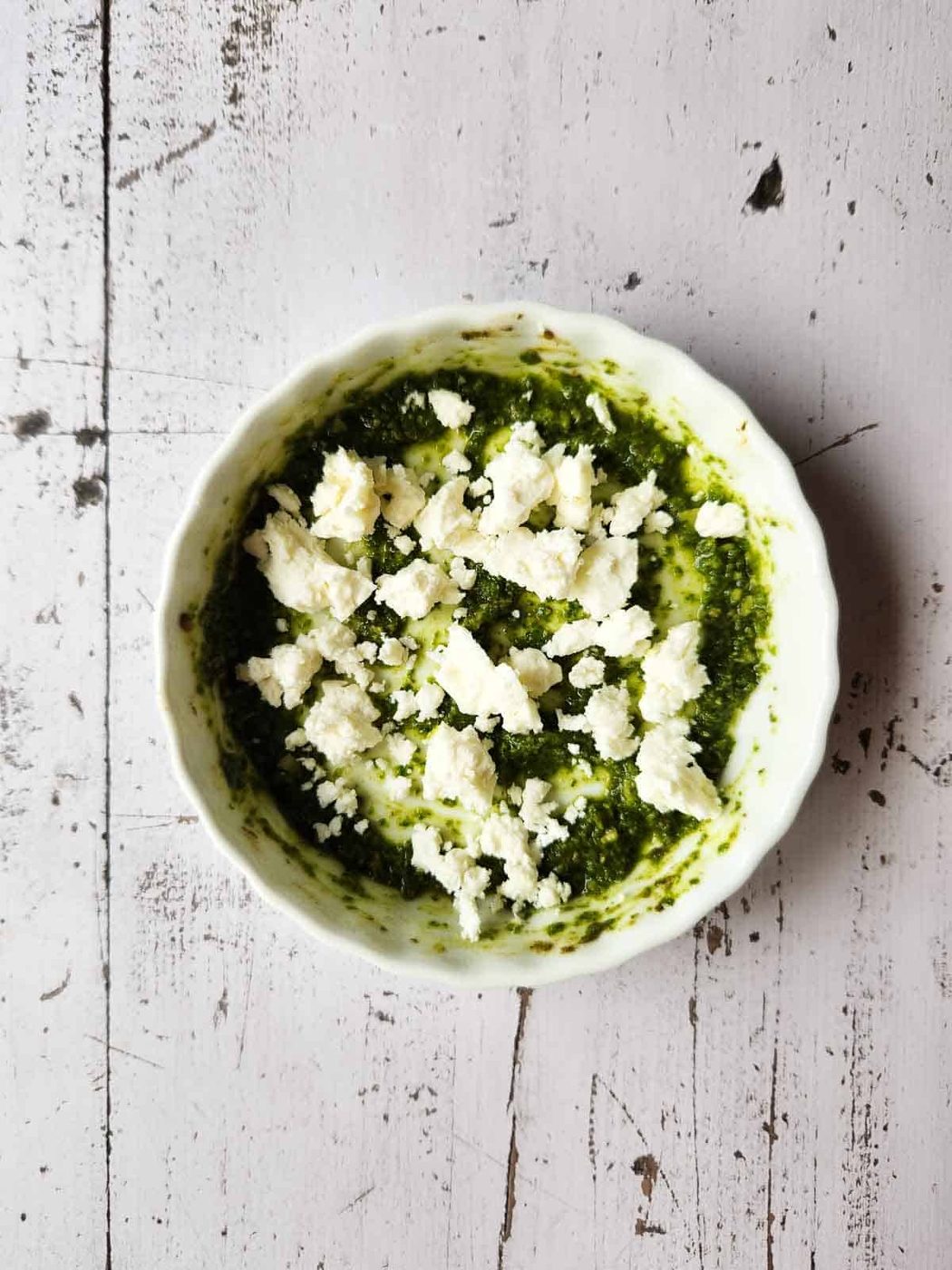 Pesto sauce and feta in a white ramekin.