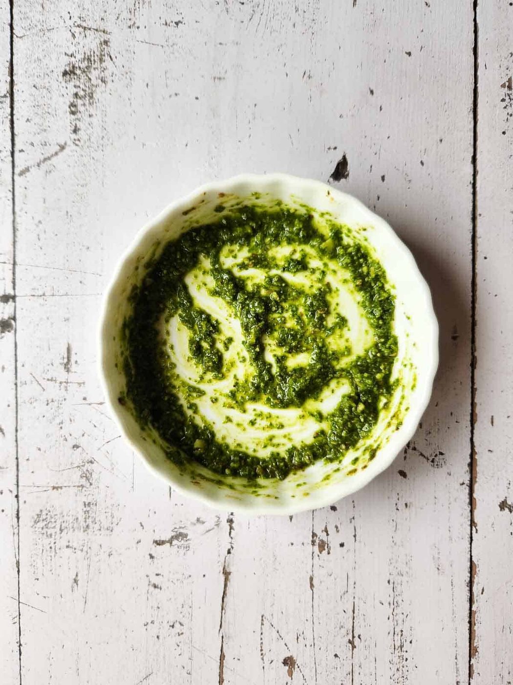 Pesto sauce in a white ramekin.