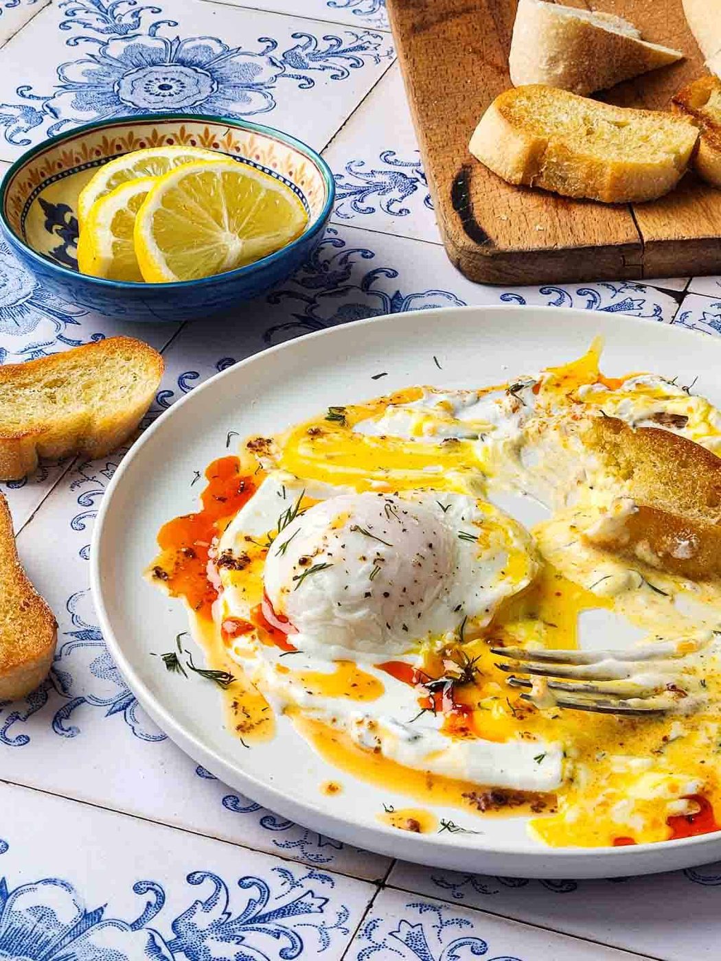 A table view of chili-poached eggs half eaten, with bread dunked in the egg.