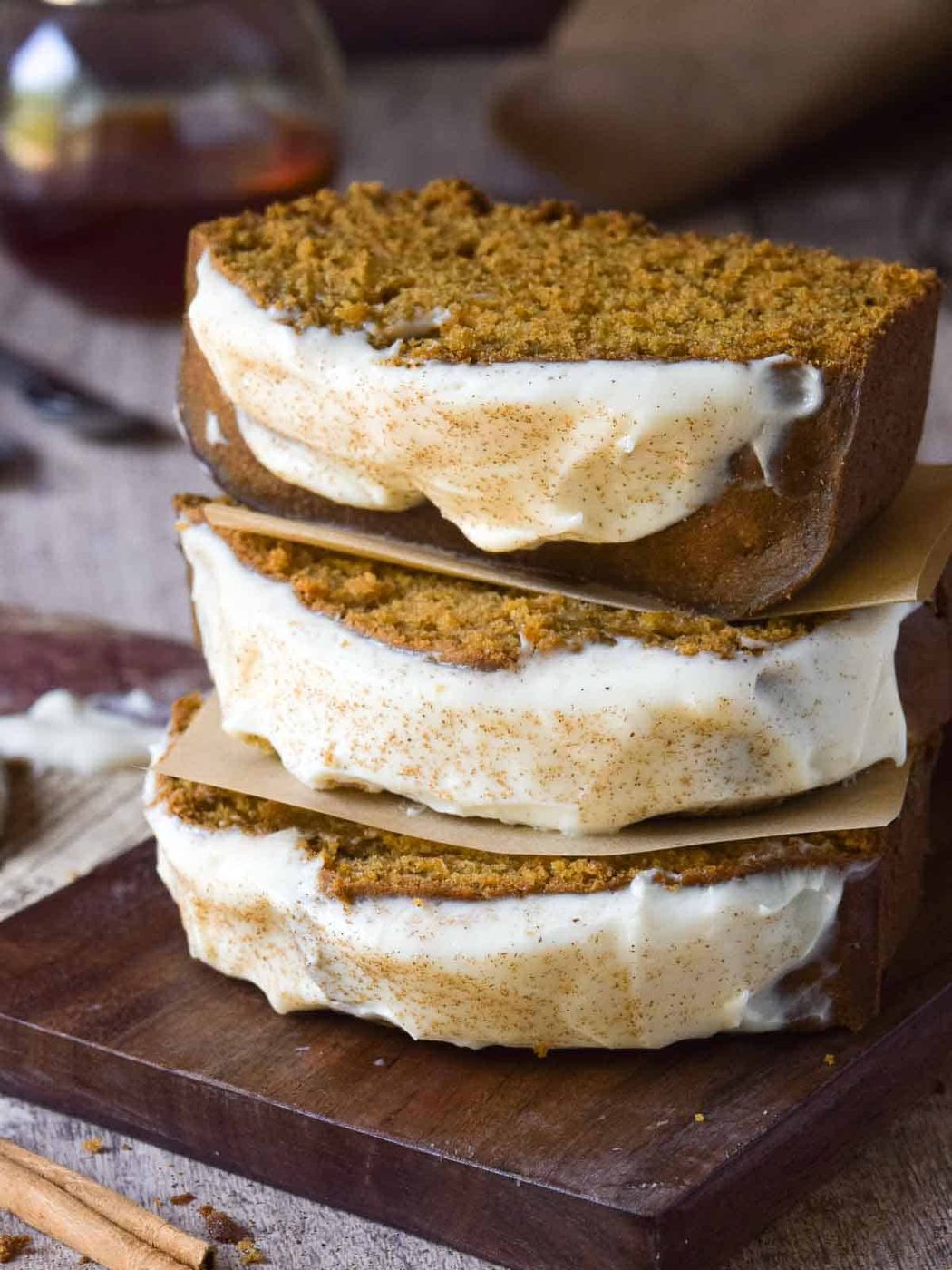 Three slices of Pumpkin Bread and Maple Cream Cheese Frosting stacked on top of each other.