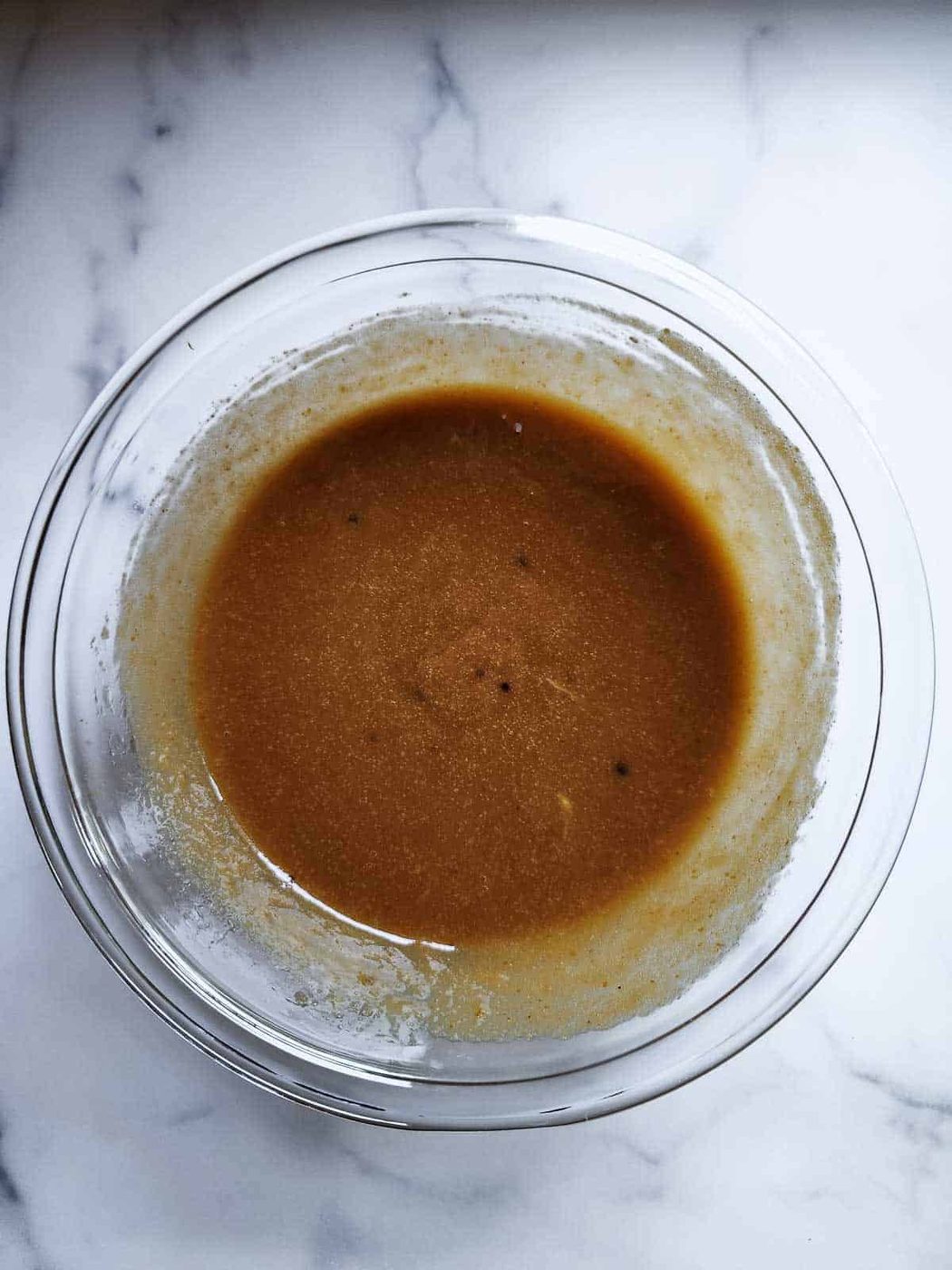 Blended wet ingredients in a clear bowl for pumpkin bread.