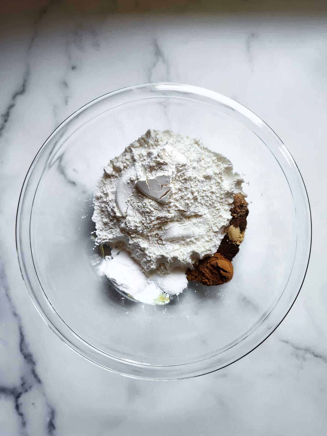 Dry ingredients in a clear bowl for pumpkin bread.