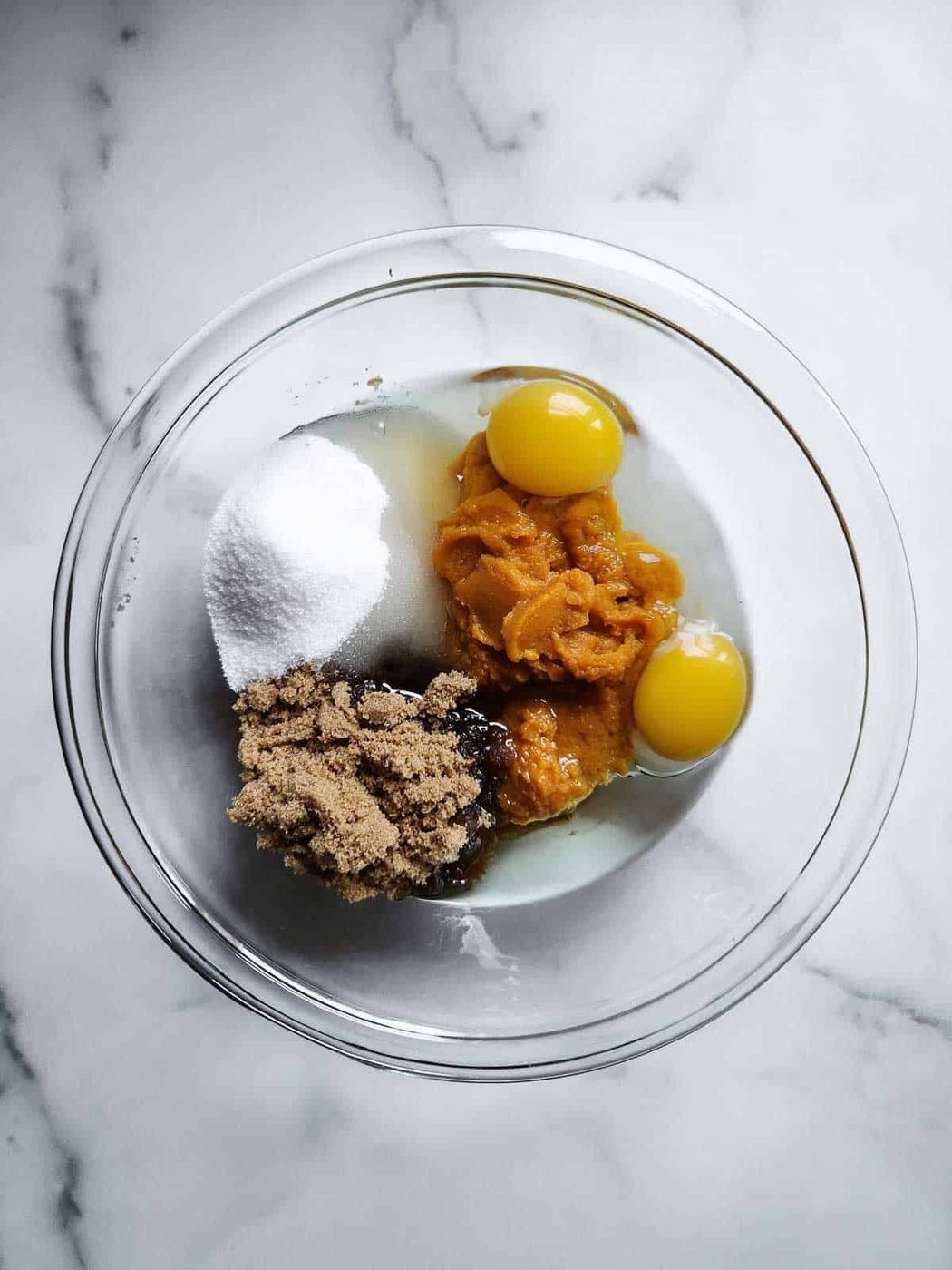 Wet ingredients in a clear bowl for pumpkin bread.