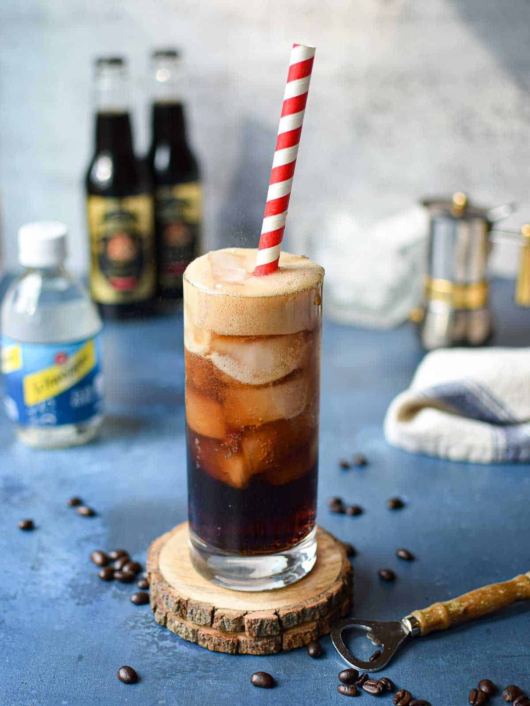 Espresso soda in a glass with a red straw on top of a blue surface.