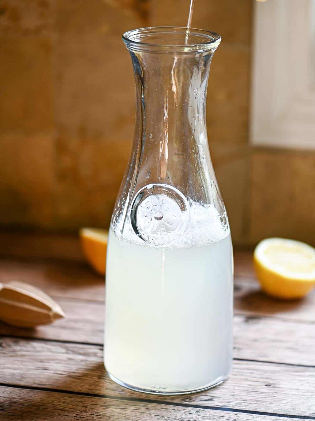 A pitcher filled with lemonade on a wooden table.