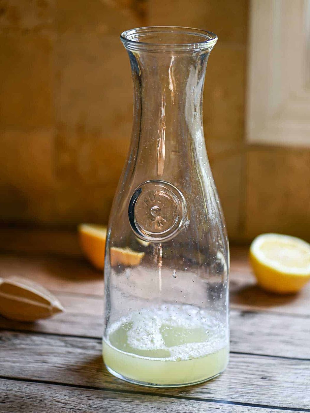 A pitcher filled with lemon juice on a wooden table.