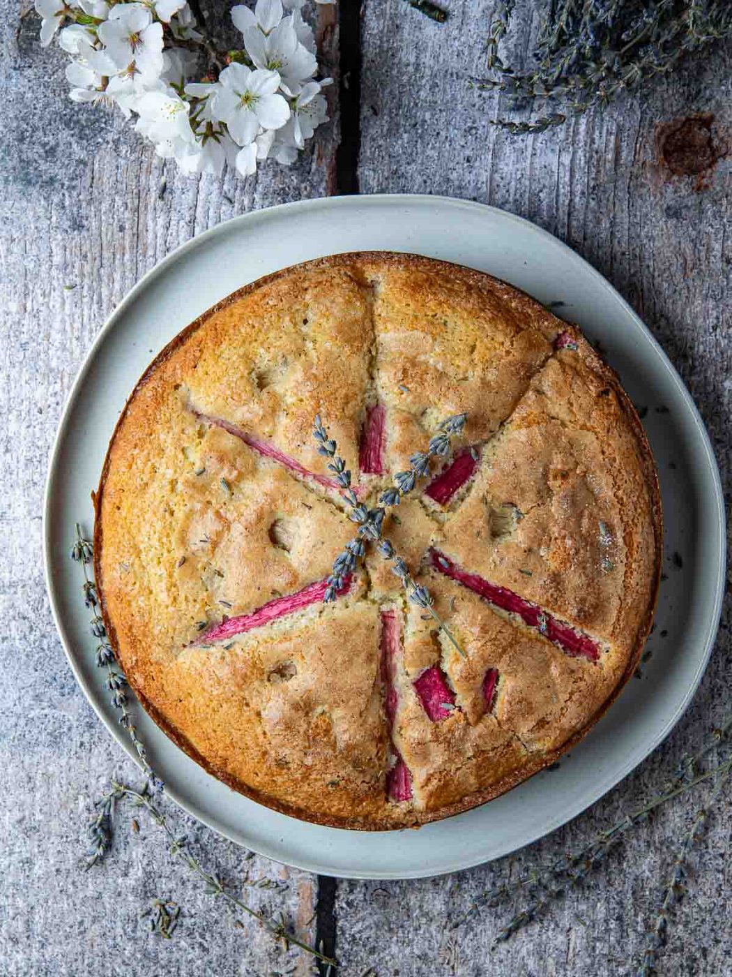 Overhead of rhubarb lavender cake on light wood board.