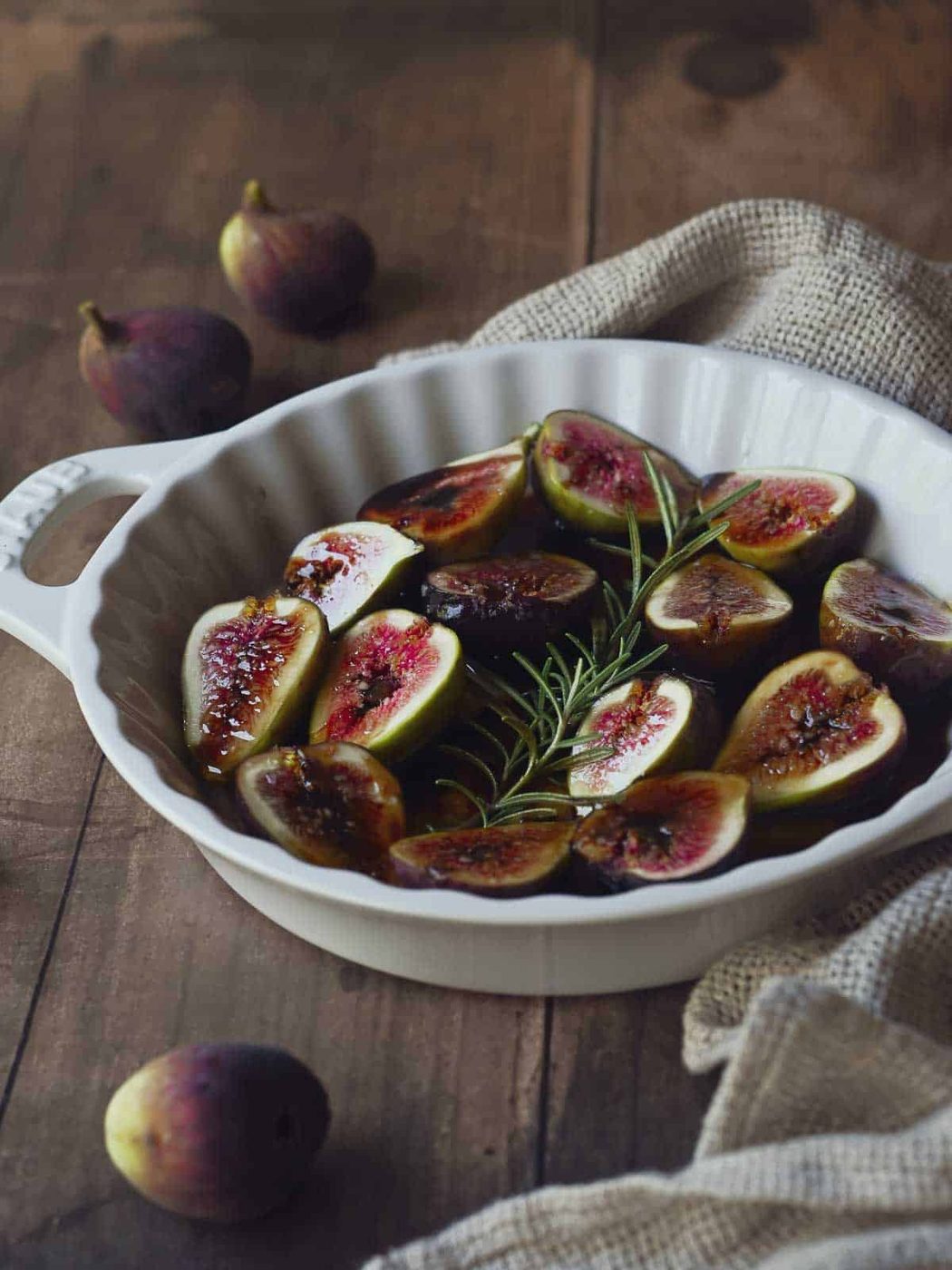 Fresh figs in a baking dish with rosemary and balsamic.