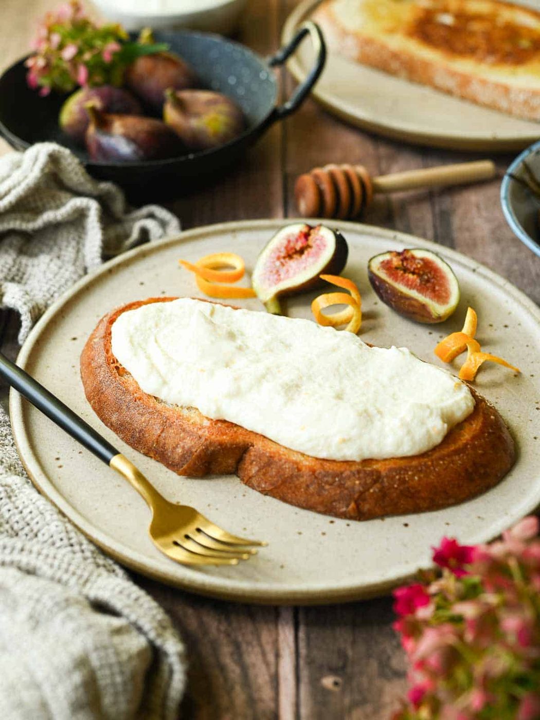 Toasted bread with ricotta on top on a beige plate.